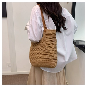 Detail of hand-woven hollow mesh tote bag with dark brown leather straps for summer