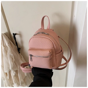 Detail of pink mini backpack featuring woven texture, front pocket, and slim shoulder straps