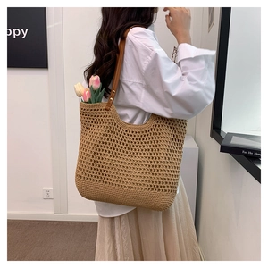Detail of hollow woven beach tote bag with brown leather shoulder strap and tulip decor