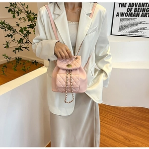 Détail du mini sac à dos rose matelassé avec fermoir rotatif en métal et bandoulière chaîne