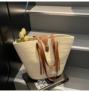 Detail of woven tote bag with premium leather straps and buckle on modern stairs