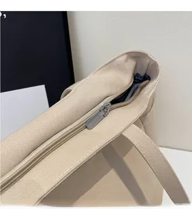 Close-up of smooth metal zipper detail on off-white canvas tote bag with thick texture
