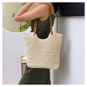 Detail of hollow woven beach tote with brown leather handles and golden metal rivets