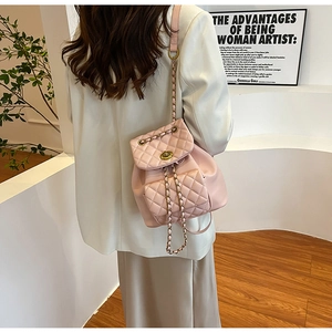 Sac à dos matelassé rose avec détails dorés et bandoulière chaîne sur modèle
