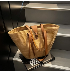 Close-up of woven cotton tote bag with brown leather straps and decorative tassel