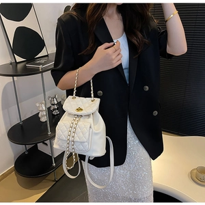 Détail du sac à dos blanc en cuir matelassé avec chaîne dorée et fermoir pivotant