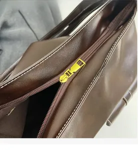 Detail of dark brown leather tote with golden zipper and white contrast stitching