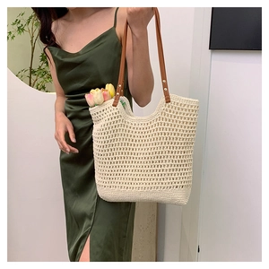 Detail of cream crochet beach tote with brown leather strap and hollow weave texture