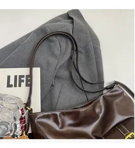 Detail view of dark brown faux leather tote with adjustable strap on professional suit