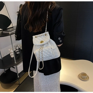 Détail d'un sac à dos blanc matelassé avec fermoir doré et bandoulière en chaîne