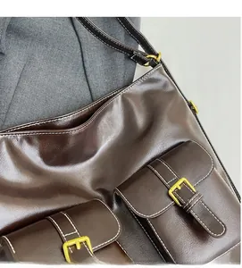 Detail of dark brown tote bag with white contrast stitching and gold buckle pockets