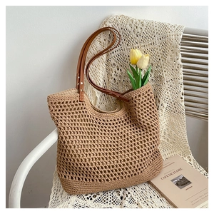 Close-up of hollow weave pattern and brown leather handle on handmade straw beach tote bag