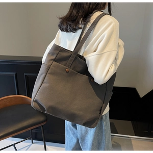 Detailed view of large canvas tote bag with dual front pockets and brass snap buttons