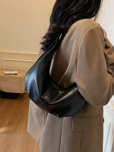 Chic black crescent moon shoulder bag in matte leather shown on model in stylish setting