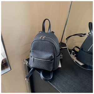 Close-up of mini black backpack featuring carbon fiber texture and dual zipper detail