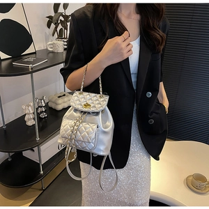 Détail d'un mini sac à dos argenté matelassé avec fermoir doré et bandoulière chaîne