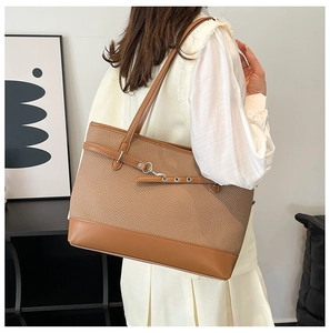 Detail einer braunen Web-Tote-Bag mit Lederriemen, getragen von einem Modell im Raum