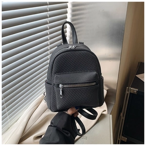 Close-up of a mini black woven backpack featuring a dual-zipper design and leather handle