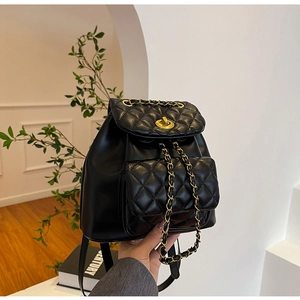 Détail d'un sac à dos en cuir noir matelassé avec fermoir doré et cordon de chaîne