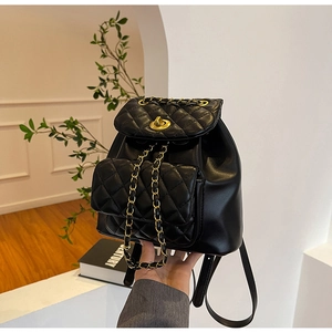 Détail de la texture en cuir matelassé noir et de la bandoulière chaîne dorée du sac