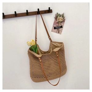 Detail of hollow-out woven texture on straw tote bag with brown leather strap