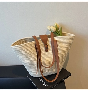 Detail of white woven tote bag with brown leather straps and vintage metal buckle
