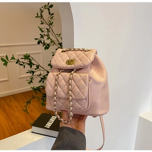 Vue détaillée du sac à dos matelassé rose avec bretelles en chaîne dorée et fermoir pivotant