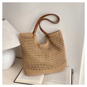 Detail of hollow-out mesh straw tote with brown leather handles and gold rivet reinforcement