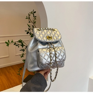 Détail du sac à dos matelassé argenté avec fermoir rotatif doré et bandoulière