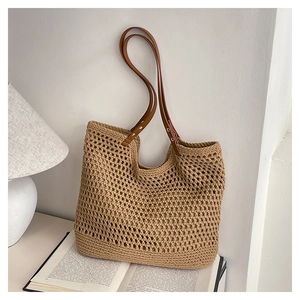 Detail of hollow woven tote bag with brown leather handles and metal rivet accents