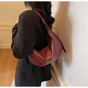 Deep red leather crescent shoulder bag styled with a black blazer for a chic autumn look