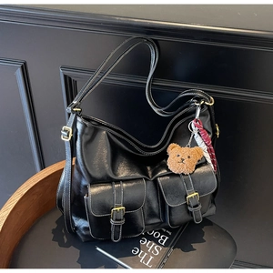 Detail of black tote bag featuring contrast white stitching and fuzzy bear charm