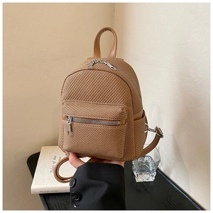 Detail of a brown woven mini backpack featuring synthetic leather trim and silver metal zippers