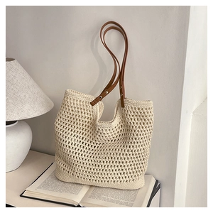 Detail of hollow-out woven straw tote with brown leather handles on vintage books