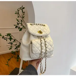 Détail d'un sac à dos blanc en cuir matelassé avec fermoir doré et cordon chaîne