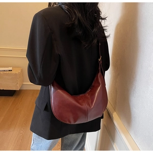 Detailed back view of a burgundy half-moon crossbody bag worn over a black blazer