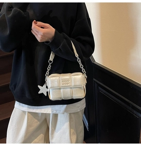 Détail d'un sac à bandoulière tressé blanc cassé avec chaîne en métal et breloque étoile