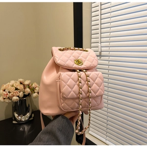 Détail d'un sac à dos rose matelassé avec chaînes dorées et fermoir pivotant