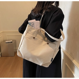 Close-up of beige canvas tote bag with front pocket and vintage brown button detail