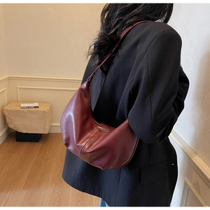 Deep burgundy leather crescent hobo bag with sleek shoulder strap shown on model in studio