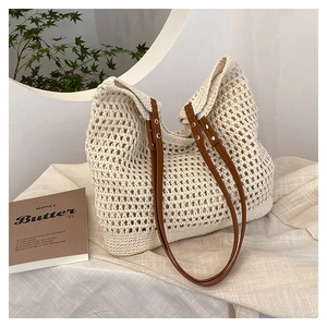 Detail of hollow woven beach bag featuring contrast brown leather straps and metal rivets