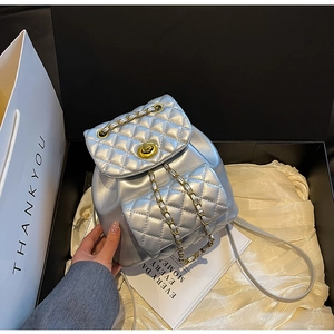 Détail d'un mini sac à dos argenté matelassé avec chaîne dorée et coffret cadeau