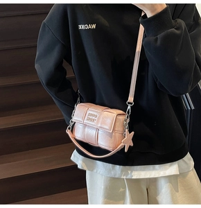 Détail du sac bandoulière rose tressé avec finition brillante et breloque étoile