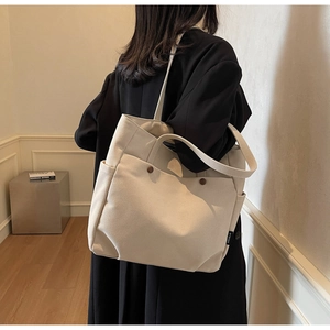 Detailed view of beige canvas tote bag with brown button accents and dual handles