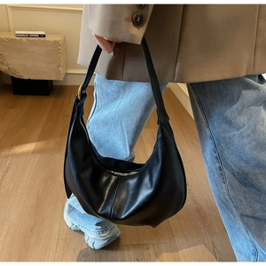 Detail of black hobo bag with smooth leather texture and large gold buckle hardware