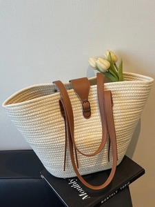 Large straw tote bag with brown leather straps and woven texture for beach and commute