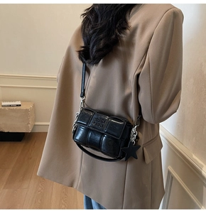 Détail du sac à bandoulière tressé noir avec chaîne argentée et pendentif étoile