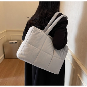 Detail of light blue quilted puffer tote bag showing soft texture and thick strap