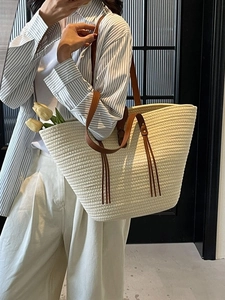 Large capacity woven tote bag with brown leather straps and tassel detail for beach use