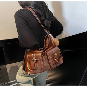 Detail of brown vintage tote bag featuring double buckle pockets and a cute teddy charm